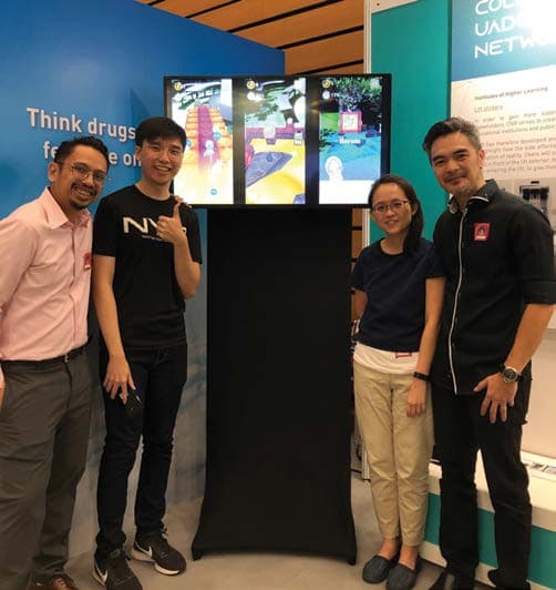 Four people at an exhibition booth with Seal No To Drugs shown on the display behind them