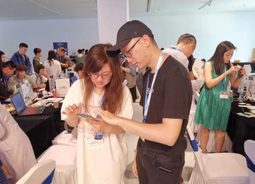Visitors looking at a handheld device during a public game demonstration